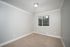 Bright and airy bedroom with plush carpeting, large window offering natural light, and elegant crown molding.
