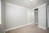Bright and airy bedroom with a large mirrored closet, fresh carpet, and elegant crown molding.