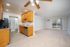 Bright, open-concept living space featuring a modern kitchen with wooden cabinetry, granite countertops, and a spacious living room with large windows and natural light.