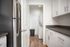 Modern kitchen with sleek stainless steel refrigerator, ample cabinetry, and a dedicated laundry nook featuring a stacked washer and dryer.