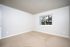 Bright, spacious room with fresh carpet and a large window offering a serene view of trees.