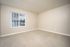 Bright, spacious room with soft carpet flooring and a large window offering a serene view, ideal for a cozy bedroom or office space.