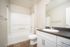 Modern bathroom with sleek fixtures, elegant white cabinets, and refined wood-style flooring.