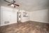 Inviting living room with elegant wooden flooring, ceiling fan, and open access to a modern kitchen, perfect for entertaining.