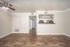 Inviting open-concept living area with elegant wood flooring and recessed lighting, seamlessly leading to a modern kitchen with stainless steel appliances.