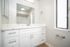 Bright and modern bathroom featuring a sleek white vanity, large mirror, and frosted window for natural light.