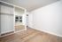 Bright and modern room with elegant hardwood floors, featuring a spacious mirrored closet and large windows for natural light.