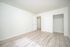 Bright and spacious bedroom with sleek wood flooring and ample closet space in a modern apartment.