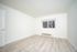 Bright and spacious room with elegant wood flooring and a large window offering scenic outdoor views.