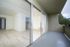 Modern apartment with sleek glass doors opening to a spacious balcony, featuring elegant hardwood floors and abundant natural light.