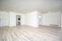 Bright and airy open-concept living space with sleek wooden floors, crisp white walls, and modern lighting.