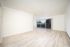 Spacious, sunlit living area with sleek laminate flooring and large sliding glass doors opening to a balcony.
