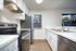 Modern kitchen with sleek stainless steel appliances, elegant white cabinetry, and bright natural light from the window.