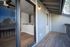 Inviting apartment balcony with wood flooring and view into modern interior with stylish lighting and sleek kitchen design.