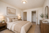 Elegant bedroom with neutral tones, featuring a plush bed, wooden furniture, and cozy decor for a serene ambiance.