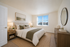 Bright and inviting bedroom with tasteful decor, featuring a cozy double bed, soft beige tones, and a sunny window view.