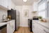Bright, modern kitchen with sleek stainless steel appliances, elegant white cabinets, and rich wood flooring, creating a welcoming culinary space.