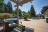 Charming outdoor patio with cozy wicker seating, lush greenery, and a sparkling pool surrounded by serene trees.