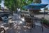 Charming outdoor patio with modern grill, stylish table set, and relaxing loungers under leafy trees, perfect for entertaining.