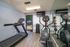 Modern apartment fitness room featuring a treadmill, elliptical, vibrant mirrored wall, and thoughtful storage for a convenient workout experience.