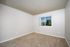 Inviting bedroom with plush carpet and bright natural light from a large window overlooking serene greenery.