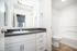 Modern bathroom with sleek vanity, large mirror, and bright lighting, offering a spacious and elegant design.