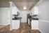 Modern kitchen with sleek stainless steel appliances, pristine white cabinetry, and elegant wood flooring.