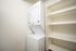 Compact laundry room with efficient stackable washer and dryer, featuring ample built-in shelving for convenient storage.