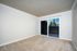 Bright, spacious living room with plush carpeting and large glass doors leading to a scenic balcony, perfect for relaxation.