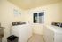 Bright laundry room featuring modern washing machines, a convenient utility sink, and a large window for natural light.