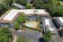 Aerial view of a stylish apartment complex with lush greenery, a sparkling pool, and modern architecture, offering a serene living environment.