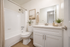 Elegant bathroom with a sleek white vanity, modern faucet, and a cozy tub, complemented by tasteful decor and warm lighting.