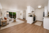 Bright and airy living room with elegant wood flooring, cozy seating area, and a modern kitchen in an open-concept apartment.
