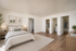 Elegant bedroom with plush bedding, serene decor, wooden flooring, and open closets.