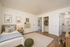 Charming bedroom with soft neutral tones, featuring a cozy bed, stylish decor, and ample closet space leading to a modern bathroom.
