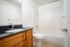 Sleek and modern bathroom with stylish wood cabinetry, a polished granite countertop, and a full-size bathtub.