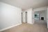 Bright bedroom with white double doors leading to a cozy living area featuring a fireplace and large balcony with scenic views.
