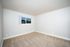 Bright and spacious bedroom with fresh carpet and a large window offering serene views.