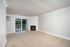 Bright and airy living room featuring a cozy fireplace, plush carpet, and sliding glass doors opening to a serene balcony view.