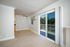 Bright living space with large sliding doors leading to a private balcony, complemented by a ceiling fan and neutral decor.