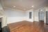 Living room with wood flooring, white wall paneling, recessed lighting, and a doorway to the bedroom.