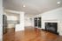 Open living area with a fireplace, wood flooring, and views of the kitchen and sliding patio door.