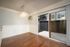 Dining area with a chandelier, wood flooring, white wall paneling, and a sliding glass door to a fenced patio.