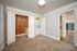 Carpeted bedroom with an open wood-lined closet, built-in drawers, and a stacked washer and dryer beside the closet.