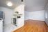 Modern open-concept living and kitchen area with sleek white cabinetry, marble tile flooring, and gleaming hardwood floors.