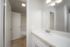 Bright and modern bathroom with sleek white vanity, spacious mirror, and elegant lighting.