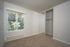 Bright bedroom with a large window, floor-to-ceiling mirrored closet, and cozy carpet flooring.