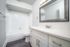 Modern bathroom with elegant white fixtures, a sleek vanity, and a large mirror, exuding a clean and luxurious feel.