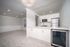 Modern open-concept apartment with pristine white cabinetry, sleek stainless steel appliances, and elegant lighting.