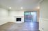 Bright and airy living room with modern flooring, cozy fireplace, and sliding glass doors leading to a private patio.
